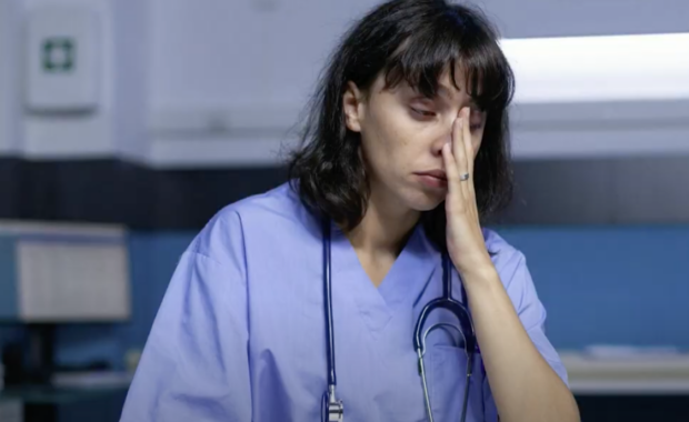 Erica, a frustrated and stressed out veterinarian slumping at desk with face in her hand